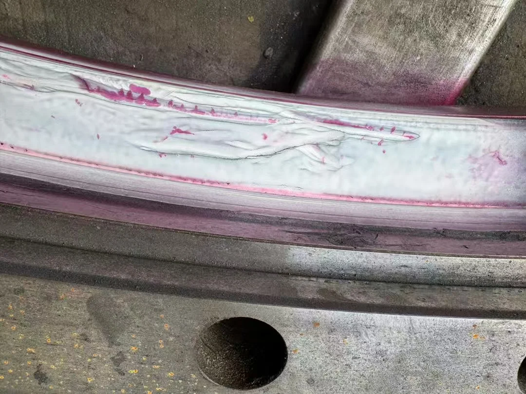 Linear magnetic particle indication along the exposed raceway substrate.